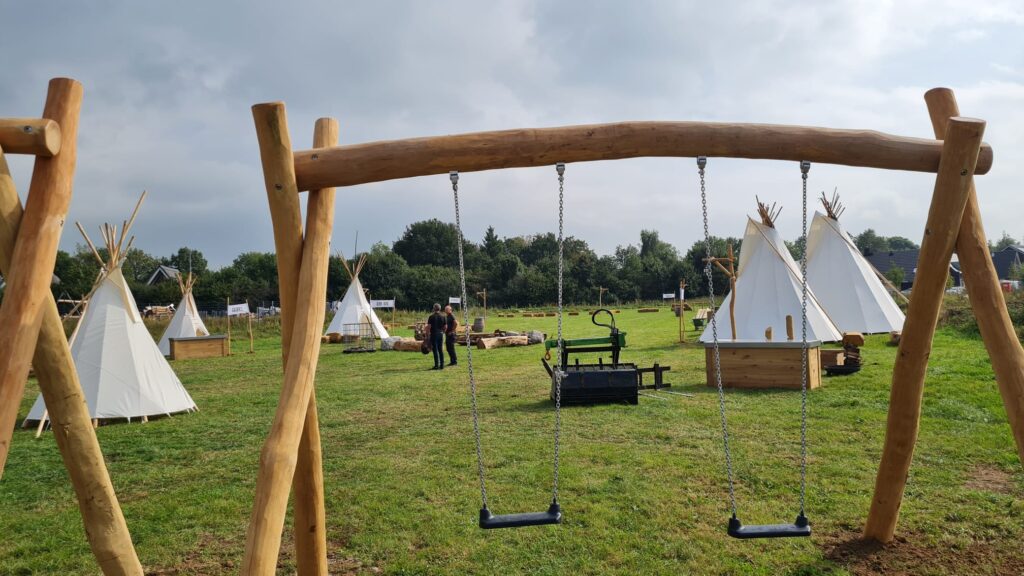 Verschillende afmetingen tipi tenten op grasveld tussen natuur speeltoestellen van boomstammen in Brabant - Yurtkopen